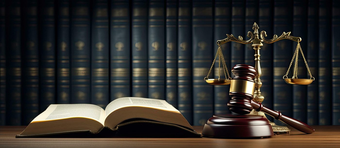 Открытая книга закона, судейский молоток на подставке и весы правосудия